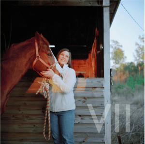 War photographer struggling with PTSD. Woman stands with horse in front of barn