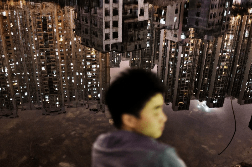 Boy with reflection of city in water in front of him