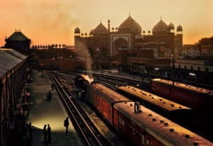 Trains in foreground with mosque in background surround by a warm orange sky