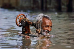 A man carries a sewing machine through neck deep water