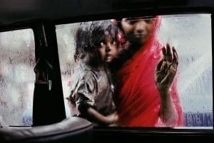 Two children look into car window, one is dressed in red