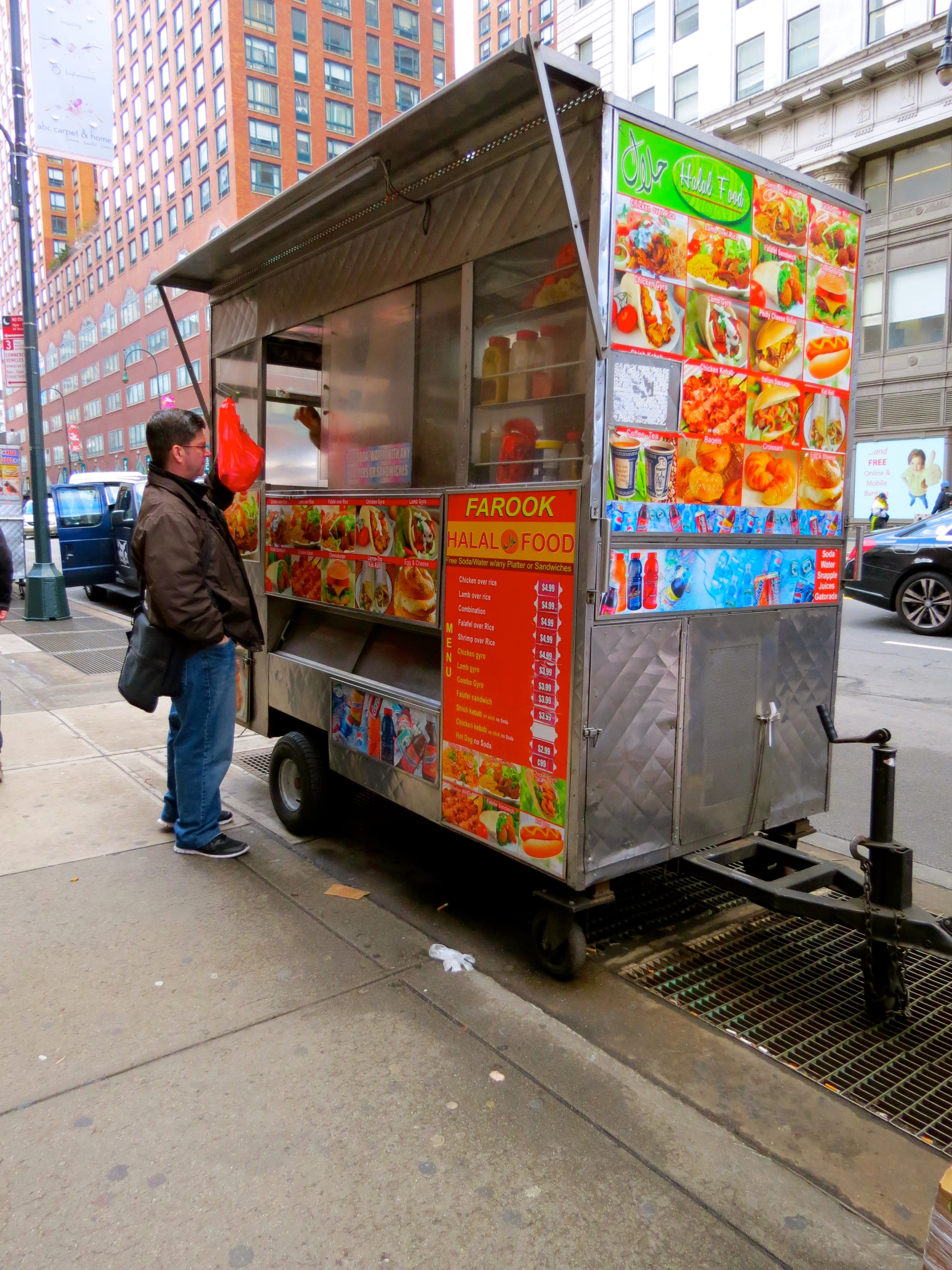 Halal truck with man standing in front of it ordering food