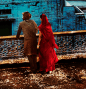 Man in brown and woman in red on balcony