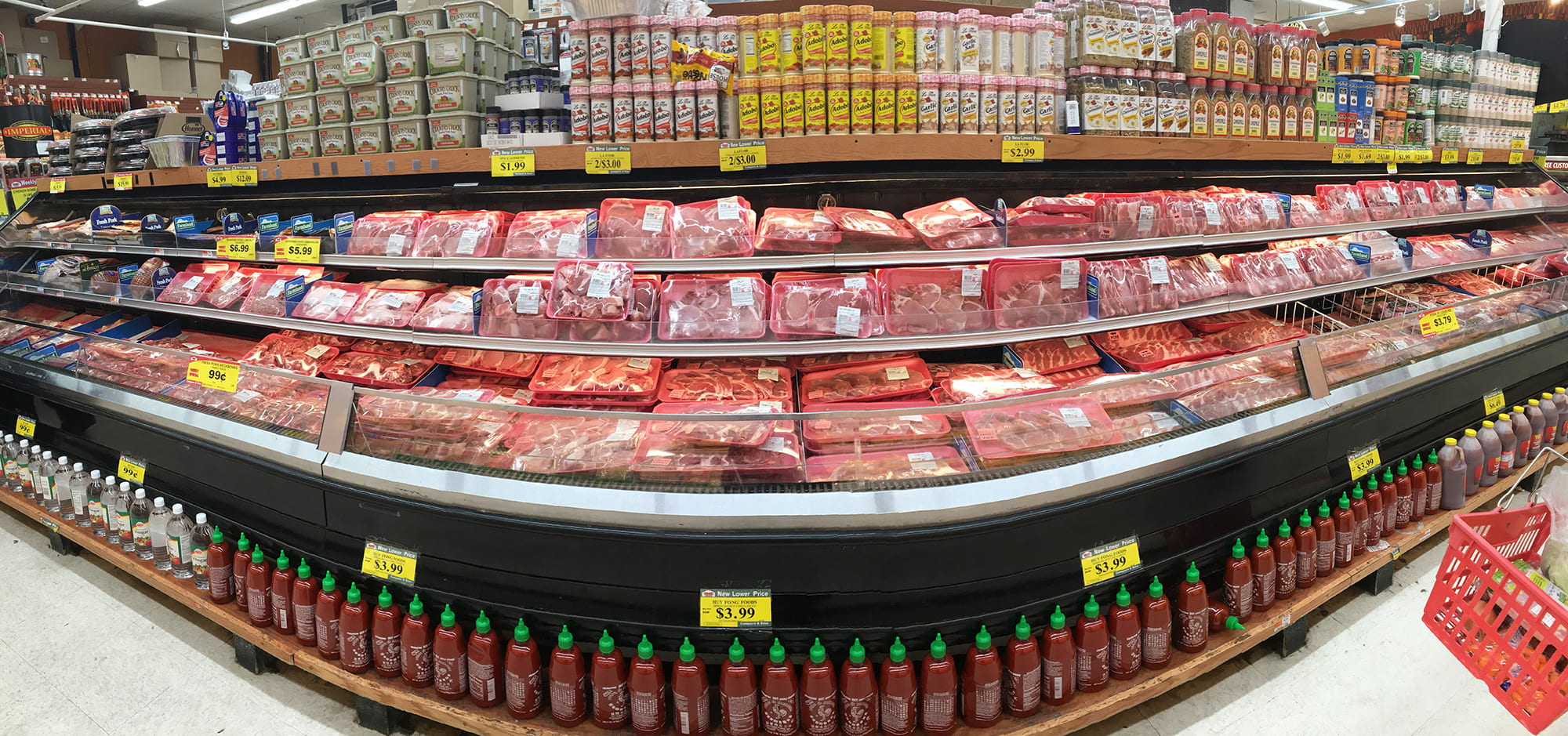 Meat section of grocery store with seasoning above fridges