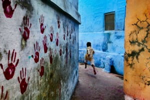 Child running barefoot through streets painted bright colors