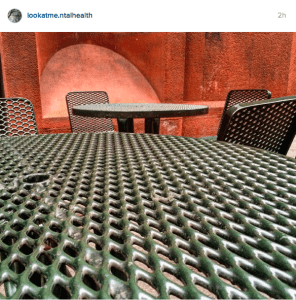 Green outdoor table with red wall in background