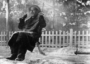 a frame from the movie Ikuru, showing the main character swinging on a swing in the playground that he built as his final legacy