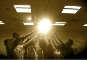 Students raising hands towards a bright light