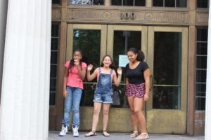 three girls standing outside building laughing