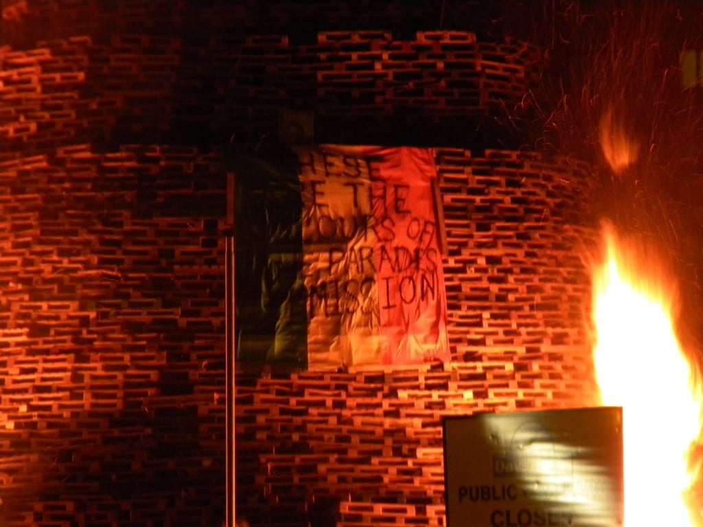 tricolor flag in front of stacked blocks with fire approaching