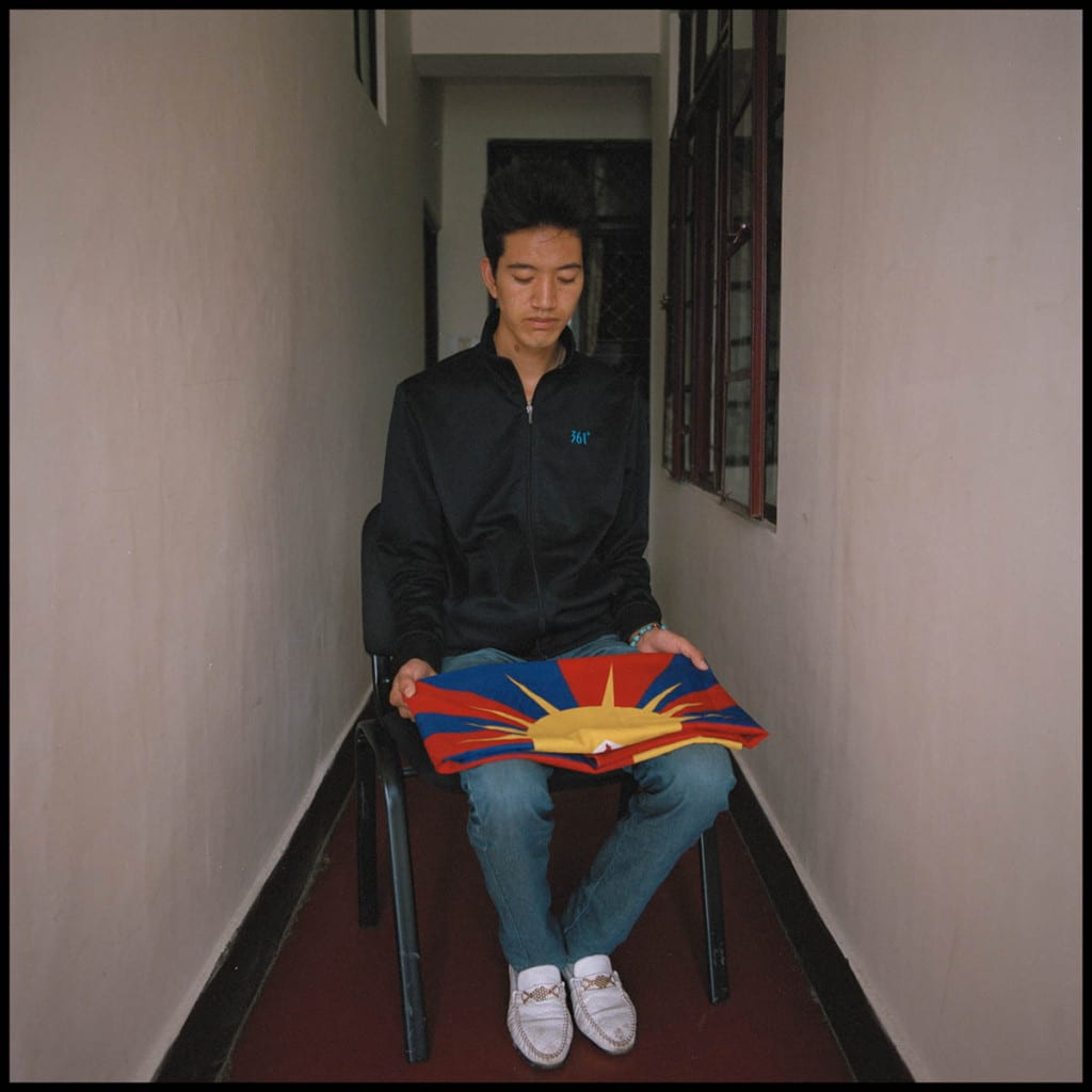 man sitting in a hall with folded flag on his lap