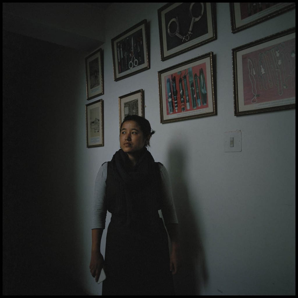 woman posing in dark room before pictures on wall