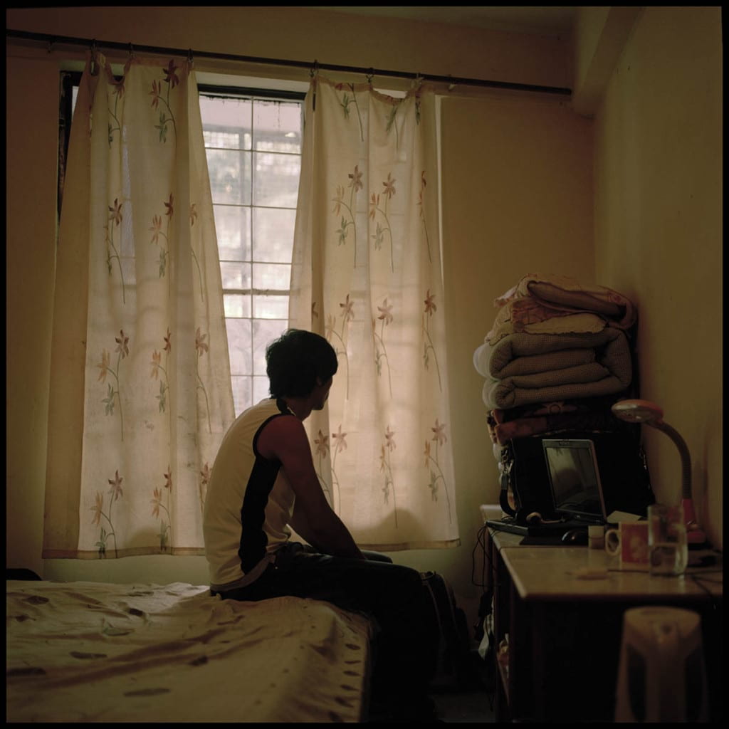 man sitting on bed in bedroom facing window