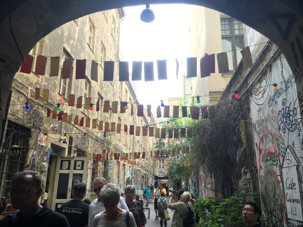 people walking in alley with colorful fanngers overhead