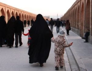 Iranian women and her child walking along road.