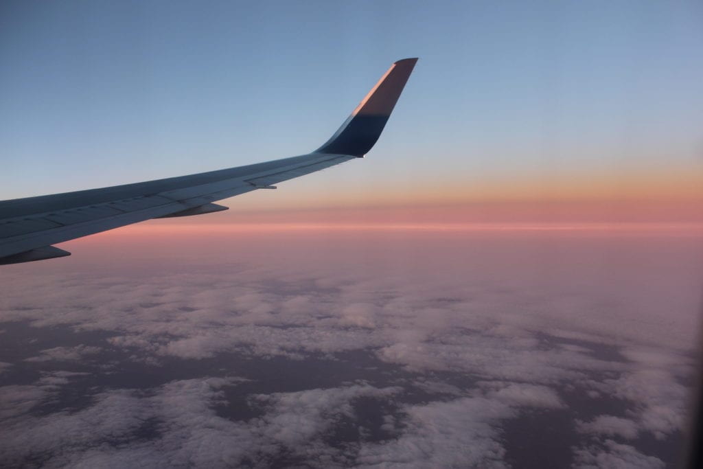 airplane wing flying at sunset