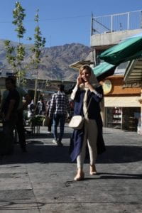 Iranian woman walking outside talking on phone