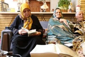 Several women gathering in a home reading the Quran 