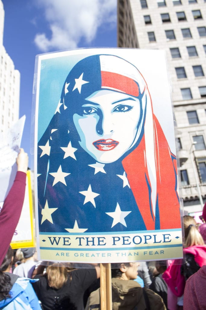 protest sign of woman in US-flag hijab with text, "We the people are greater than fear"