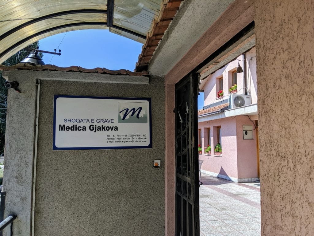 Open doorway showing a house beyond and organization sign on wall