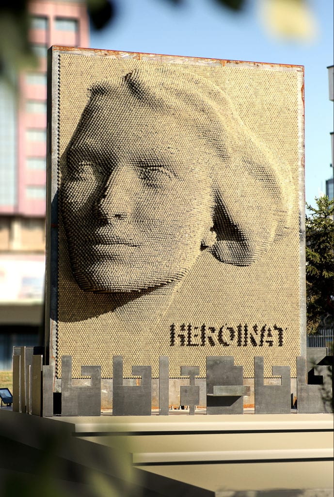 Monument with "Heroinat" written below relief of woman's face