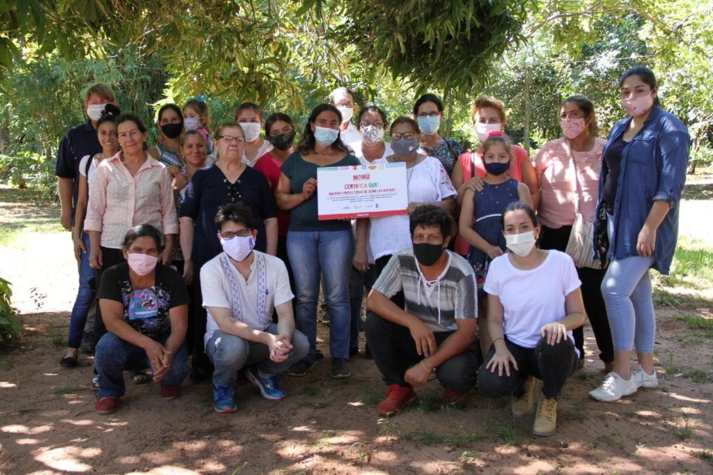 group of masked people posed under a tree