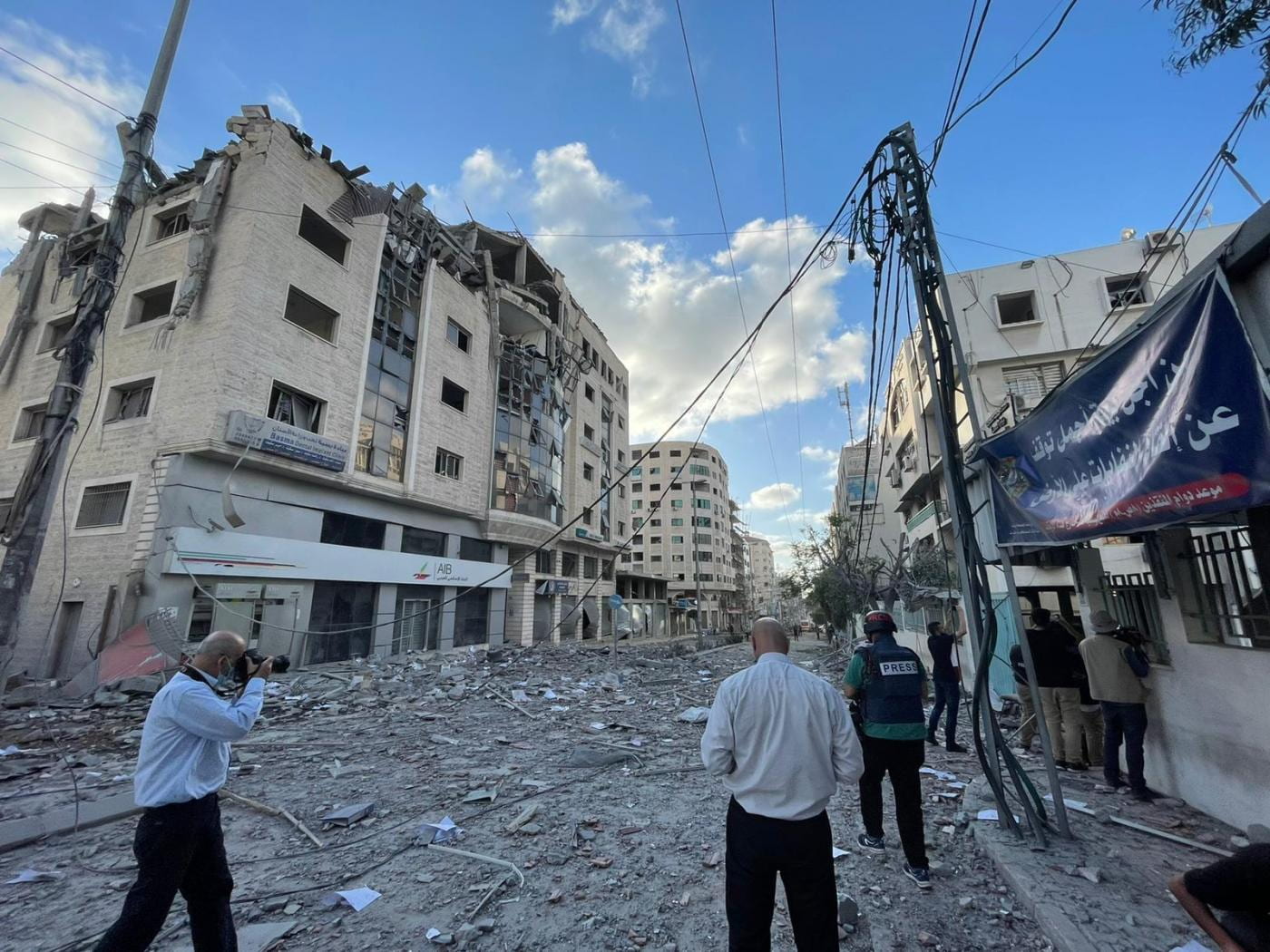 man photographing and people looking at bombed building