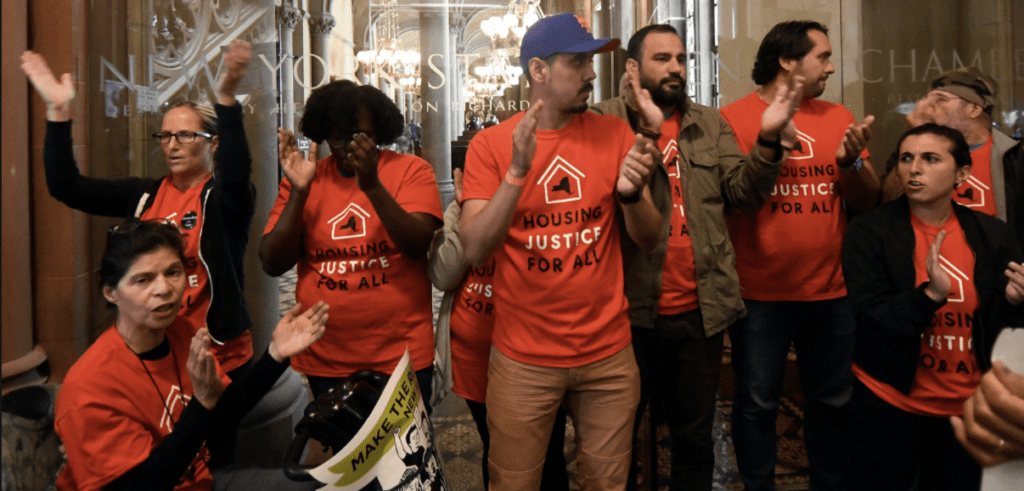 housing activists wearing orange shirts and clapping