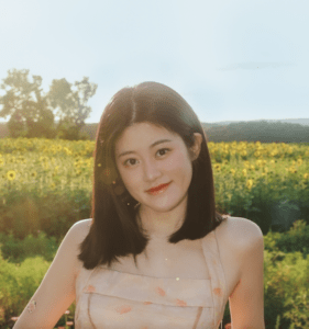 Nia (Nijia) Cui with shoulder-length hair smiling at a sunflower field