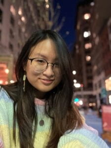 fair skinned girl with glasses wearing a rainbow sweater