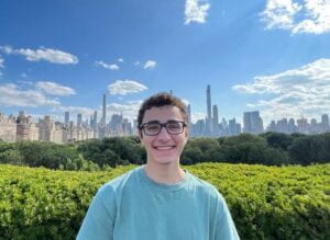 White male with brown, curly hair. Wearing glasses and a green t-shirt.